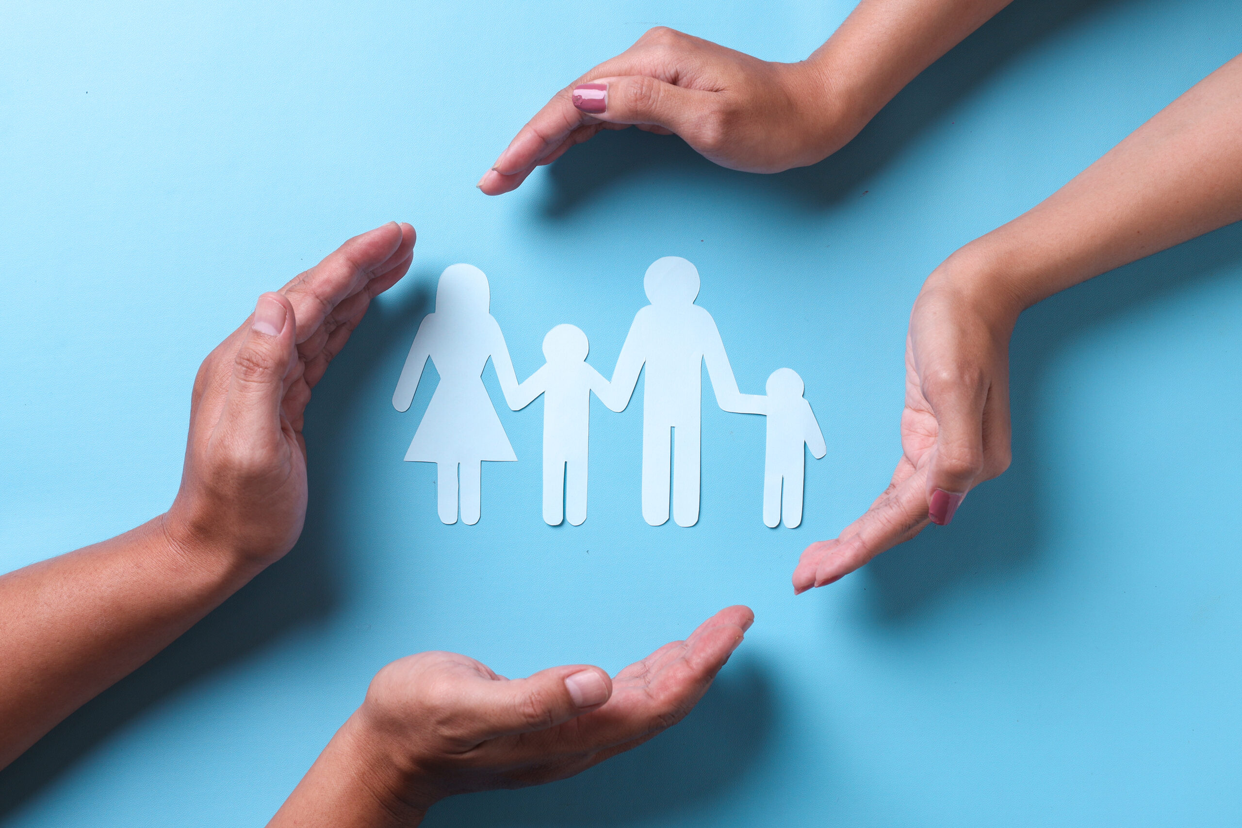 hands-covering-family-shape-on-blue-background-2023-11-27-04-50-11-utc